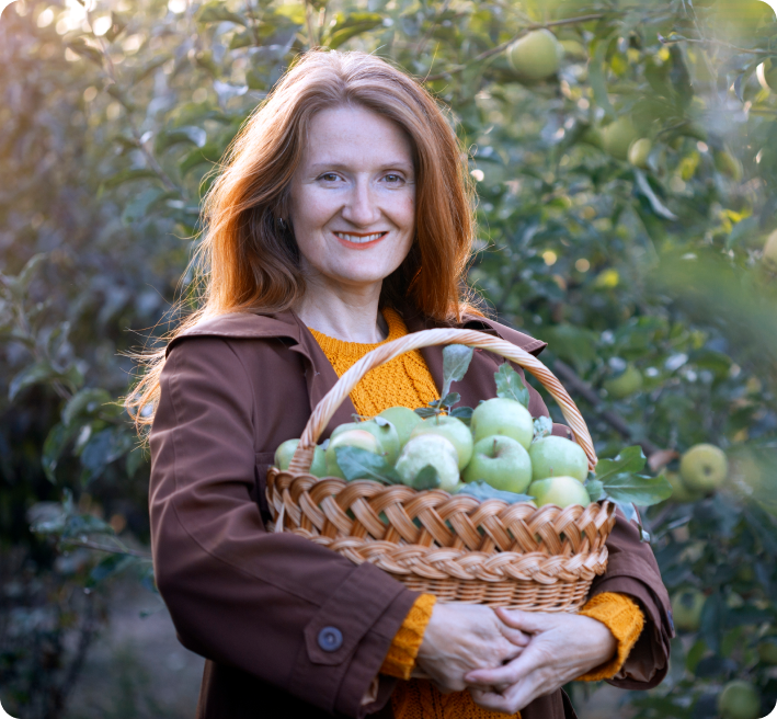 Femme tenant un panier de pommes dans un verger